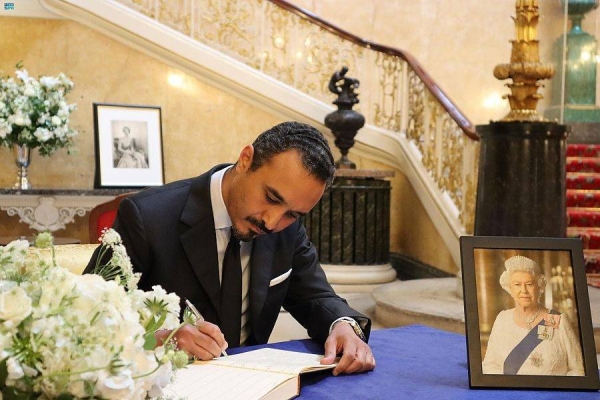 Saudi Ambassador to UK Prince Khalid bin Bandar bin Sultan writes in a book of condolence at Lancaster Palace in London on Wednesday.