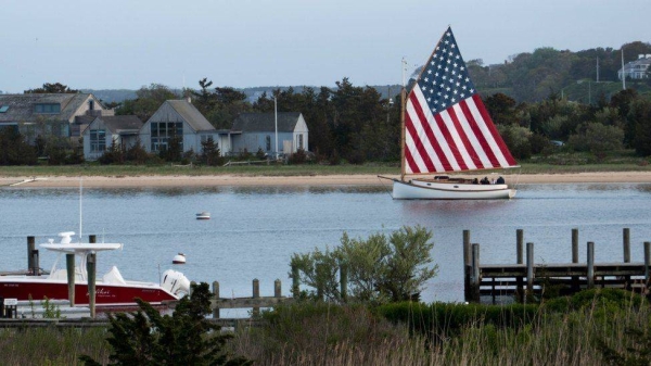 Sailboat with American-flag sail leaves Edgartown harbor, Marthas Vineyard, Martha's Vineyard is a holiday destination on the US east coast..