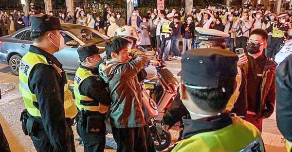 Police officers confront a man as they block Wulumuqi street, named for Urumqi in Mandarin, in Shanghai on Sunday, scene of protests against China's zero-COVID policy. — courtesy Hector Retamal / AFP