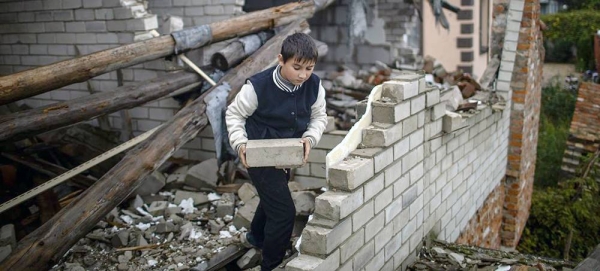 A nine-year-old boy helps his mother clear rubble from their heavily damaged home, in preparation for covering open areas with plastic as winter approaches. — courtesy UNICEF/Diego Ibarra Sánchez