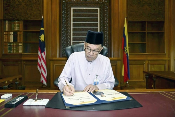 Malaysia’s new Prime Minister Anwar Ibrahim signing documents on his first day at the Prime Minister’s Office in Putrajaya. — courtesy photo