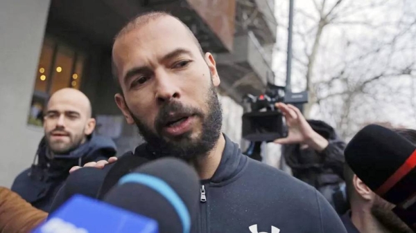 Influencer Andrew Tate speaks to the media while being escorted by police officers. — courtesy EPA