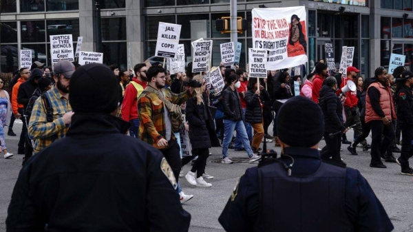 Atlanta police officers watch as protesters march during a rally against the fatal Memphis police assault of Tyre Nichols, in Atlanta, Georgia