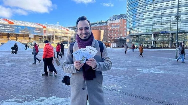 Green League candidate Ozan Yanar holding campaign leaflets in Helsinki, March 2023