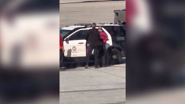 A passenger is taken into custody after opening a door of a Boeing 737 and deploying an emergency exit slide Sunday at Los Angeles International Airport
