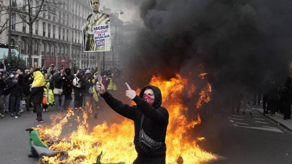 A demonstrator holds a poster mocking French President Emmanuel Macron during a demonstration in Paris on Tuesday