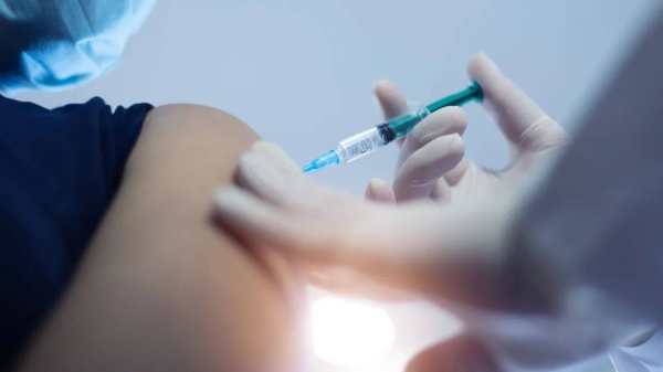 A file image of a doctor in a protective mask injecting a Covid-19 vaccine