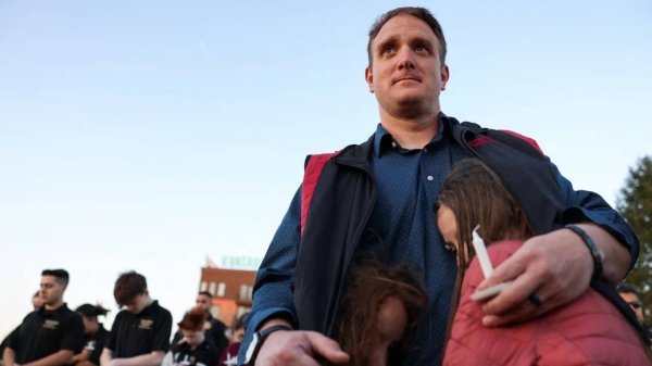 R.T. VanOrden shields his daughters from the wind during a vigil for the victims of a deadly shooting at the Covenant School in Nashville, Tennessee, Tuesday