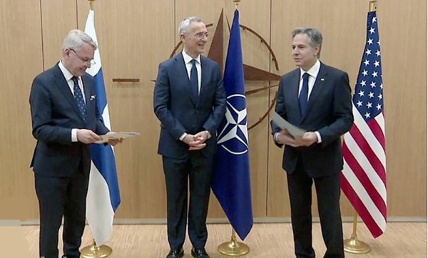The moment Finland hands over NATO documents. Finnish Foreign Minister Pekka Haavisto, left, to US Secretary of State Antony Blinken, right, with NATO Secretary General Jens Stoltenberg watching on.
