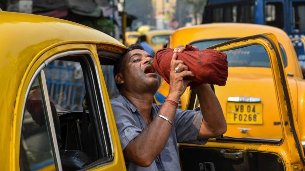 A taxi driver is seen drinking water from a bottle during afternoon heat in Kolkata, India, on April 18