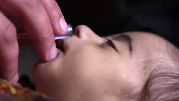 Tayabullah breathes oxygen through a tube held by his mother