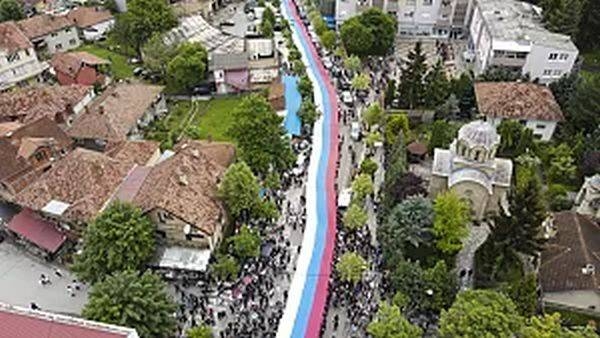 People hold a giant Serbian flag during a protest in the town of Zvecan, northern Kosovo, Wednesday, May 31