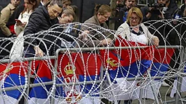 Women attach Serbian flags to a fence in front of the city hall during a protest in the town of Zvecan, northern Kosovo, on May 31.