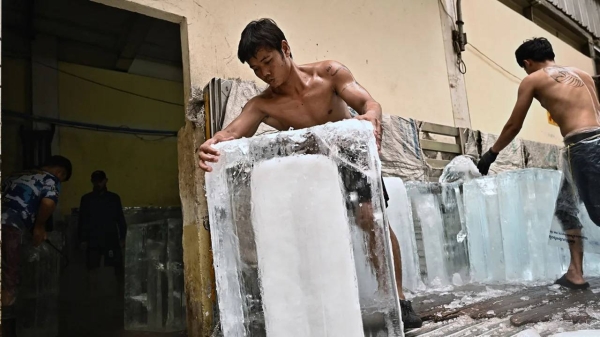 Workers move blocks of ice into a storage unit at a fresh market during heat wave conditions in Bangkok on April 25.