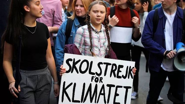 Greta Thunberg holds a sign reading, 'School strike for the climate' as she attends a climate march, in Turin, Italy, Friday 13 December 2019.