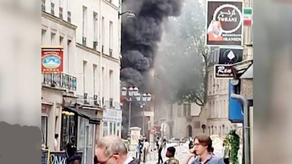 The scene shows thick black smoke coming from a destroyed building.