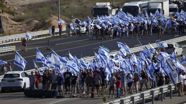Protesters waving Israeli flags block a highway near Beit Yanai.