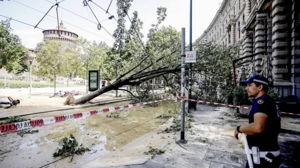 A police officer stands next to a felled tree at Castello Sforzesco after a severe storm toppled trees in Milan, Italy. — courtesy EPA