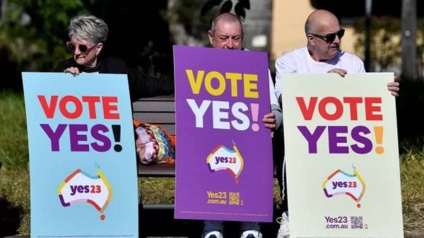 Supporters hold placards during a community event in support of the Voice