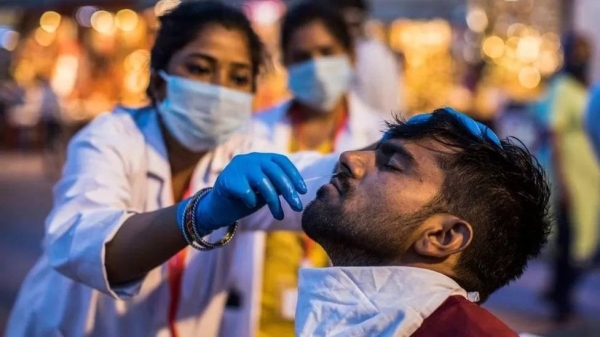 A health worker collects a nasal swab sample from a devotee during the Kumbh Mela in Haridwar in 2021