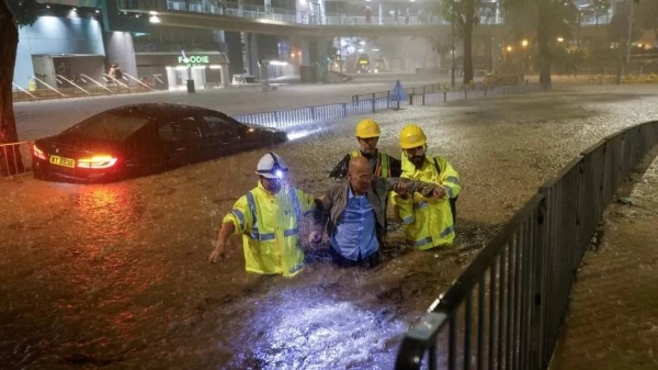 Workers rescuing a driver stranded after waters rose quickly