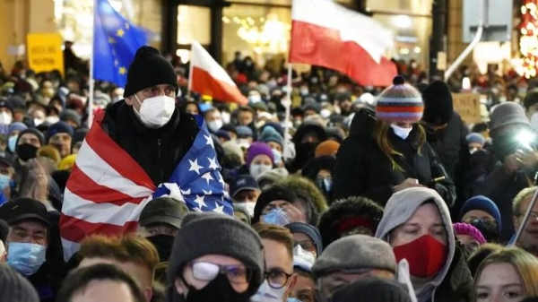 People demonstrate after the Polish parliament approved a bill that is widely viewed as an attack on media freedom, in Warsaw, Poland, Sunday Dec. 19, 2021.