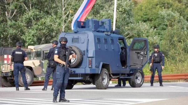 Kosovo police at the scene with troops from the US and EU states in the background. — courtesy Reuters