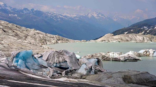 Chunks of ice covered by sheets float in a lake at the Rhone Glacier near Goms, Switzerland, 16 June 2023