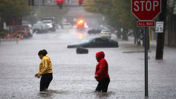 Residents walk through floodwaters in the New York City suburb of Mamaroneck in Westchester County, New York, on Friday