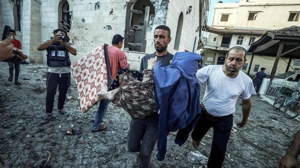 A wounded Palestinian being carried away from Al-Ahli Hospital in Gaza City