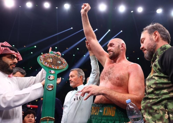 Turki Al-Sheikh, the chairman of the General Entertainment Authority. hands Tyson Fury the championship belt.