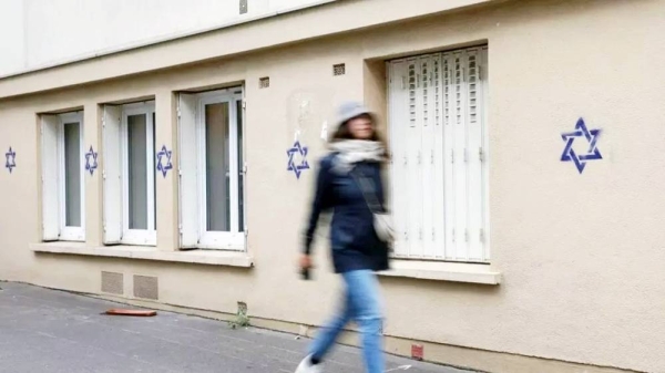 A woman walks along a building whose facade is covered with Stars of David in Paris. —AFP