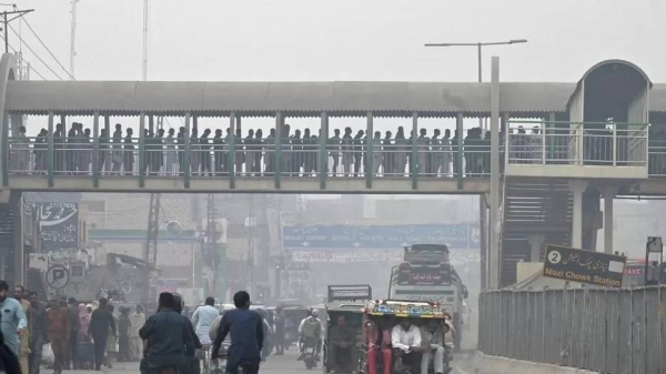 Commuters make their way through a busy street amid smoggy conditions in Lahore