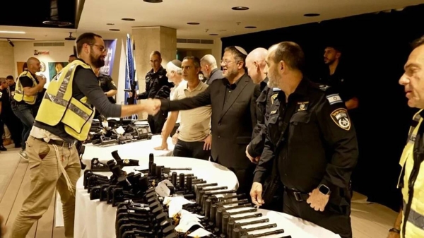 Itamar Ben-Gvir shakes hands with a civilian security squad member as he hands out rifles in Caesarea, Israel, November 2023