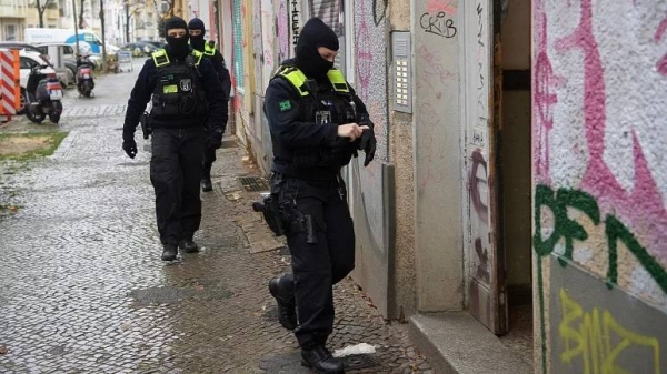 Police officers walk to the entrance of a building during a raid in Berlin, Germany