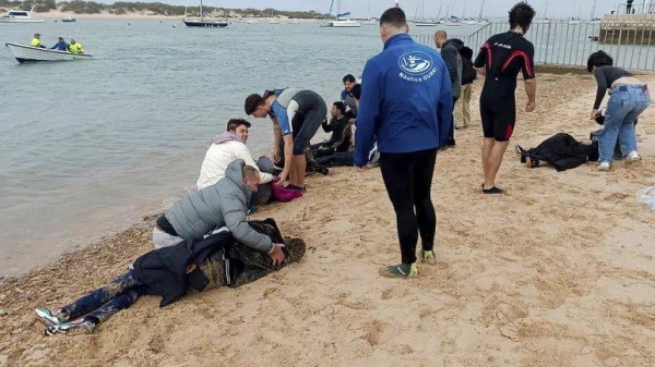 Migrants are rescued by locals on the shore of a beach, close to the southwestern city of Cádiz, Spain