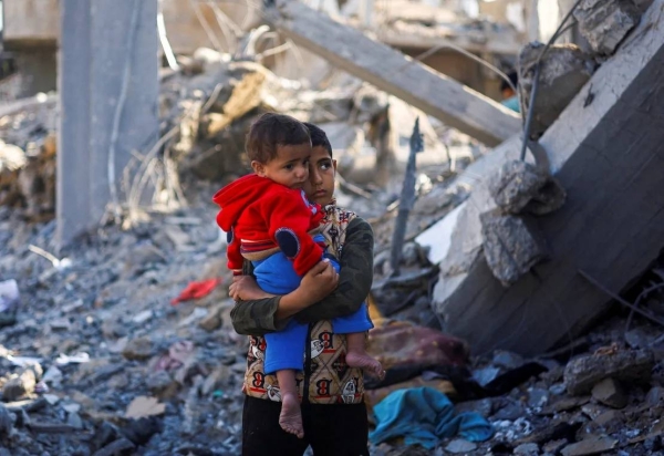 A Palestinian boy carrying a baby stands at a site of a destroyed building in Rafah, in southern Gaza, December 4, 2023