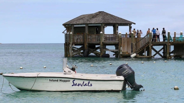 People gather on a pier after a woman was killed by a shark while paddleboarding in the Bahamas