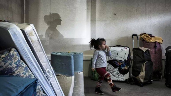 A girl walks amongst bags and mattresses as Eastern European migrants wait to temporarily settle in a locale in Decines, central-eastern France