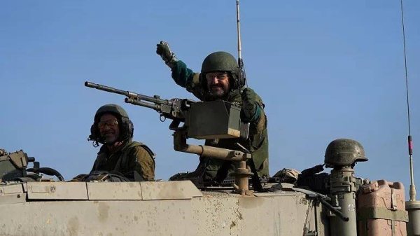 Israeli soldiers wave from a tank near the border between Gaza and southern Israel on Tuesday, Dec. 12, 2023