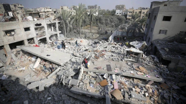 An aerial view of a destroyed residential area as Palestinians try to collect usable items under the rubbles of a building, demolished following the Israeli attacks, in Deir al-Balah, Gaza on December 12