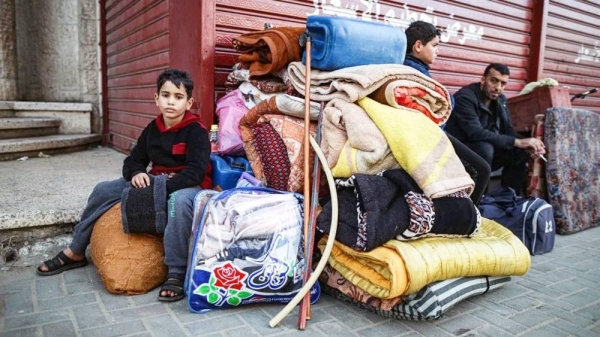 Two children and a man are pictured with a pile of belongings in the street. — courtesy Getty Images