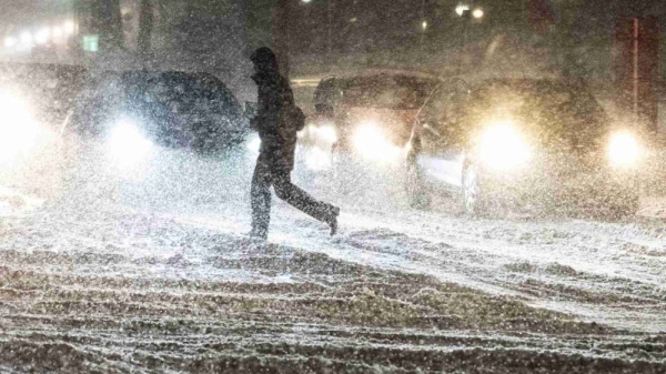 A person crosses a street during heavy snowfall in Aalborg, northern Jutland, Denmark, Wednesday, Jan. 3, 2024