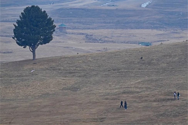 Visitors walk along ski slopes usually covered in snow at this time of the year in Gulmarg