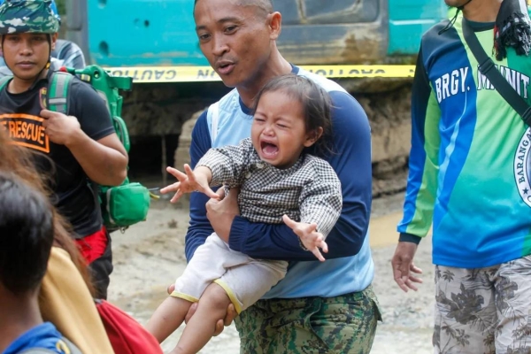 A policeman carries a baby as officials ordered mandatory evacuation from the landslide-hit village on February 8, 2024