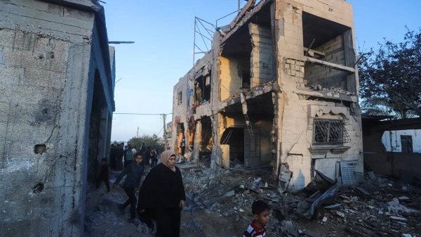Palestinians walk by a residential building destroyed in an Israeli strike in Rafah, Gaza Strip, Sunday,