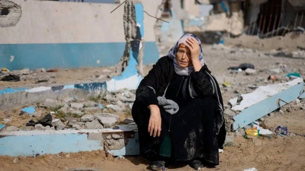 A woman sits next to a destroyed building in Rafah, southern Gaza. 