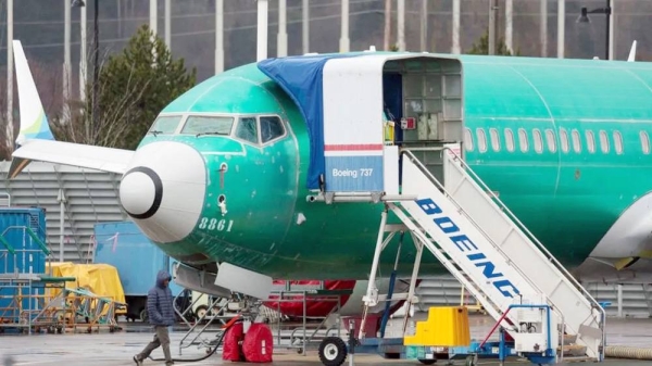 A person walks past an unpainted Boeing 737-8 MAX parked at Renton Municipal Airport adjacent to Boeing's factory in Renton, Washington. — courtesy Getty Images