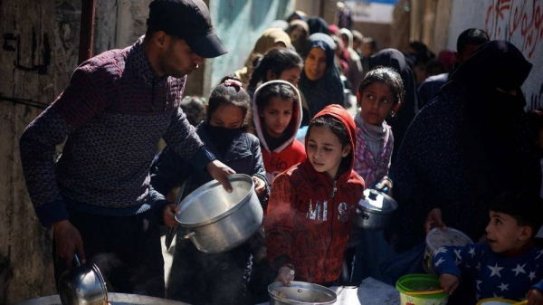 Palestinian children wait to receive food cooked by a charity kitchen amid shortages of food supplies amid the conflict between Israel and Hamas in Rafah, in the southern Gaza Strip, on March 5