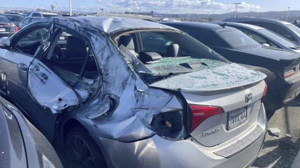 A damaged car is seen Thursday in an employee parking lot after tire debris from a United Airlines plane landed on it at San Francisco International Airport